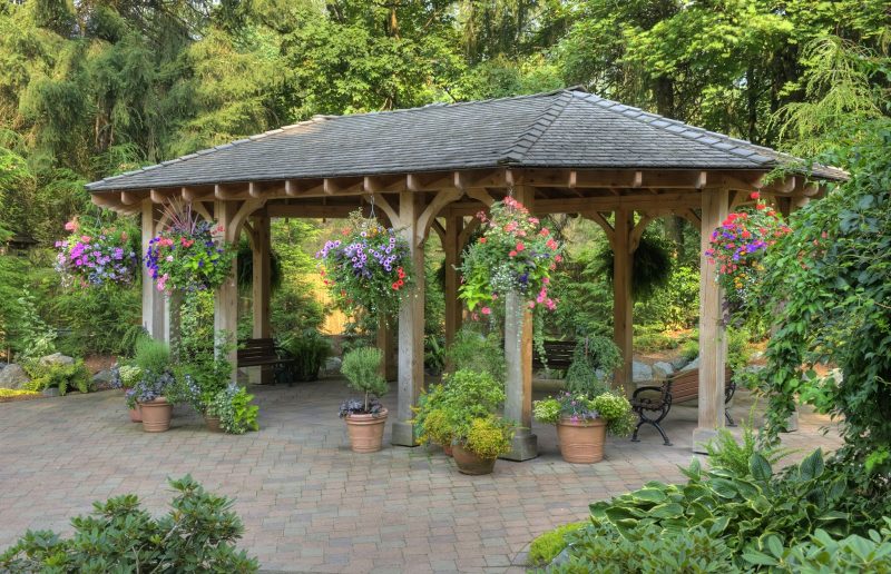 cabana posts and bench seating and terra cotta planters with beautiful variety of plants and flowers