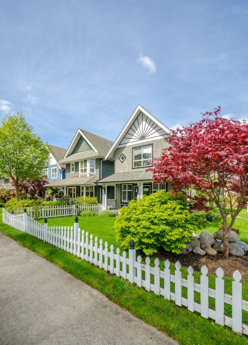 candlestick pickets with black newel posts and sun design on gabled roof and petite porch with diamond shaped small window and parterre of stones and maple