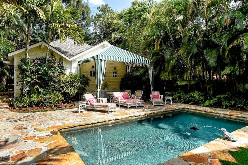classic rectangular pool with flagstone patio and pool area flooring and garden canopy with green stripes and frog fountain and hip roof with corbel accents