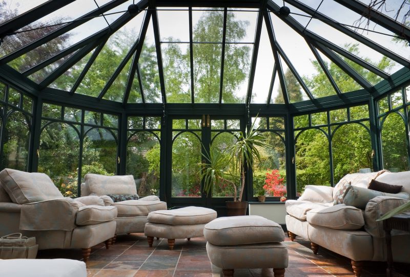 custom-built victorian conservatory sunroom with swing sunroom doors with brass upper locks and earth tone slate floor and bay curved front windows