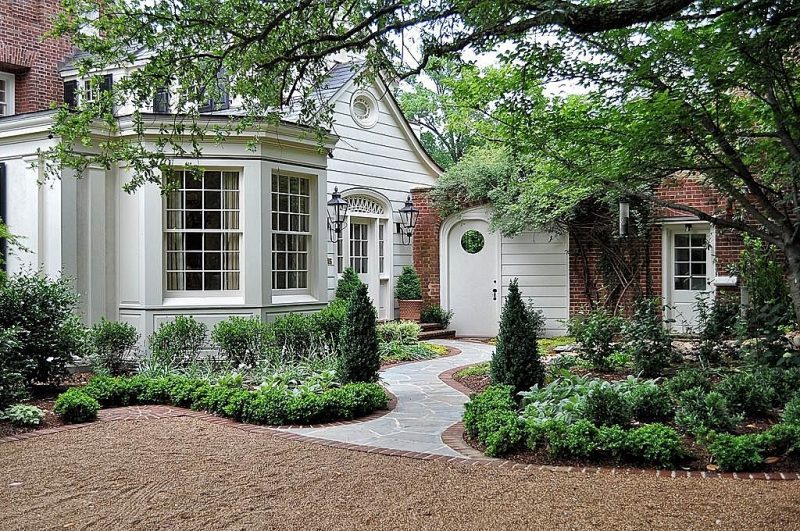 gravel driveway with irregular flagstone curved pathway and brick driveway and garden edging with brick steps and cypress trees flanking path