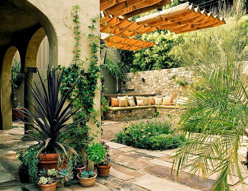 hand-designed and rolled rim pots and arch and columns entryways with built-in stacked stone bench and patio retractable awning and stone and pebble patio flooring