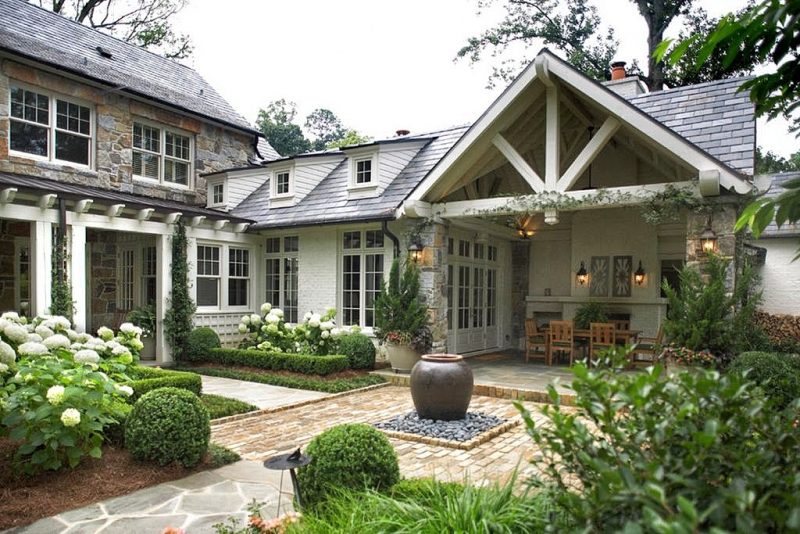 irregular flagstone path with ground topiaries flanking path and brick courtyard pavers and square river rocks patio accent with glazed water jar and hydrangea parterres