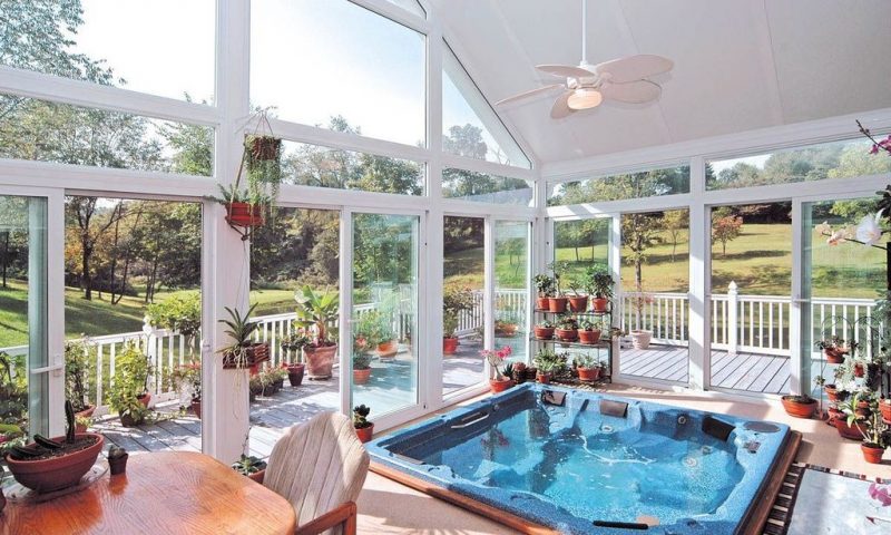 jacuzzi hot tub and transom windows in varying sizes with bonsai plants on a 3-tier iron plant stand and assortment of terra cotta planters with wraparound porch