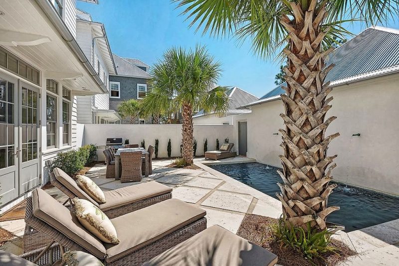 lap pool with 2 wall fountains and stamped pre-cast concrete pavers with backyard space saving in-swing 8-lite french doors and palm trees