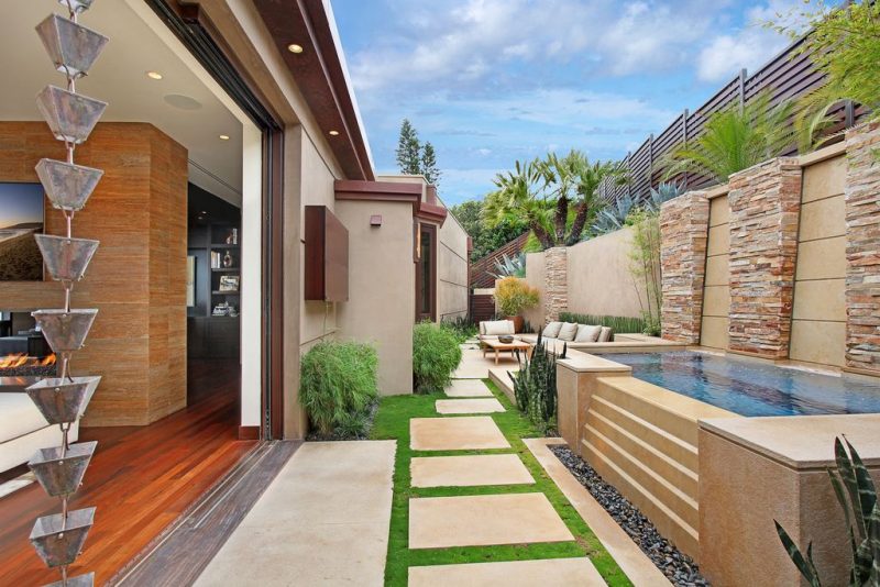 mini lap pool with water walls and pebble catch basin for pool overflow on outdoor patio with dry stacked stone pillars