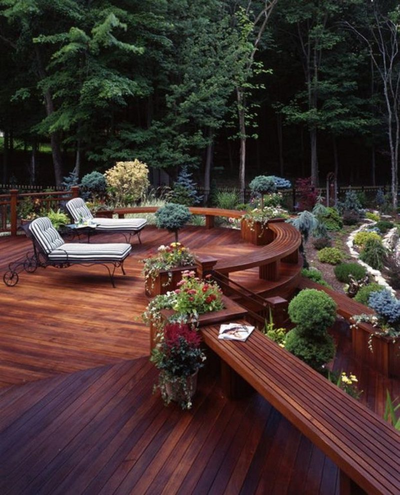 multi-level wooden deck with cascading steps with bannister and built-in semi-circle and long benches and built-in square planters and topiaries