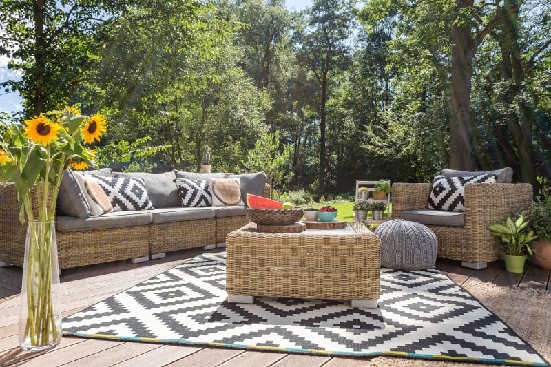 rattan-sofas-with-grey-cushioning-and-fruit-bowls-on-rattan-coffee-table-and-black-and-white-rug-pattern-with-matching-pillows