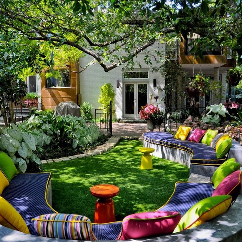 serpentine concrete banquet bench and yellow and orange West Elm martini side tables with curved stone garden edging that doubles as pathway and colorful throw pillows