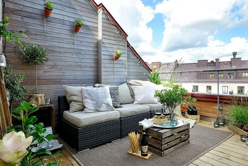 small clay pots hung by strings on wooden roof top deck with plexiglass railing and wooden crates repurposed as coffee table with salvaged wooden tray used as planter box
