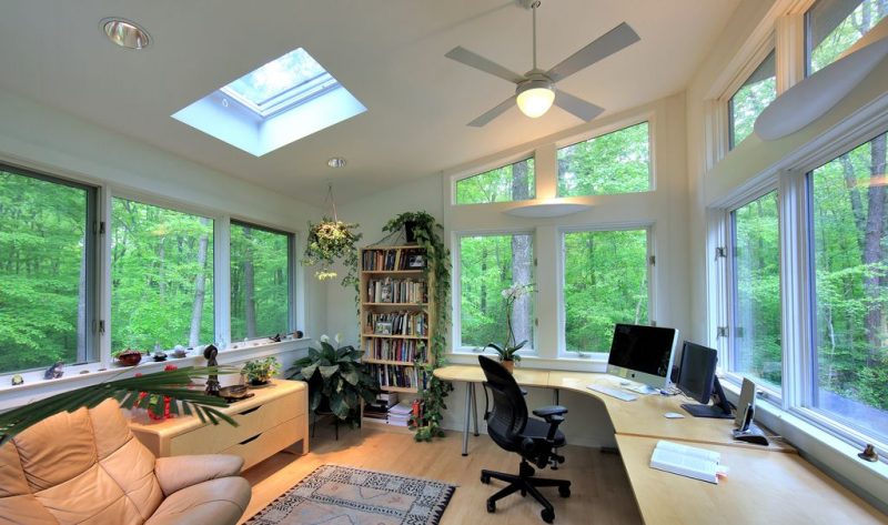 square skylight and large casement windows with transoms and white wall mount lighting fixtures with curved workstation calling back floor and window sill
