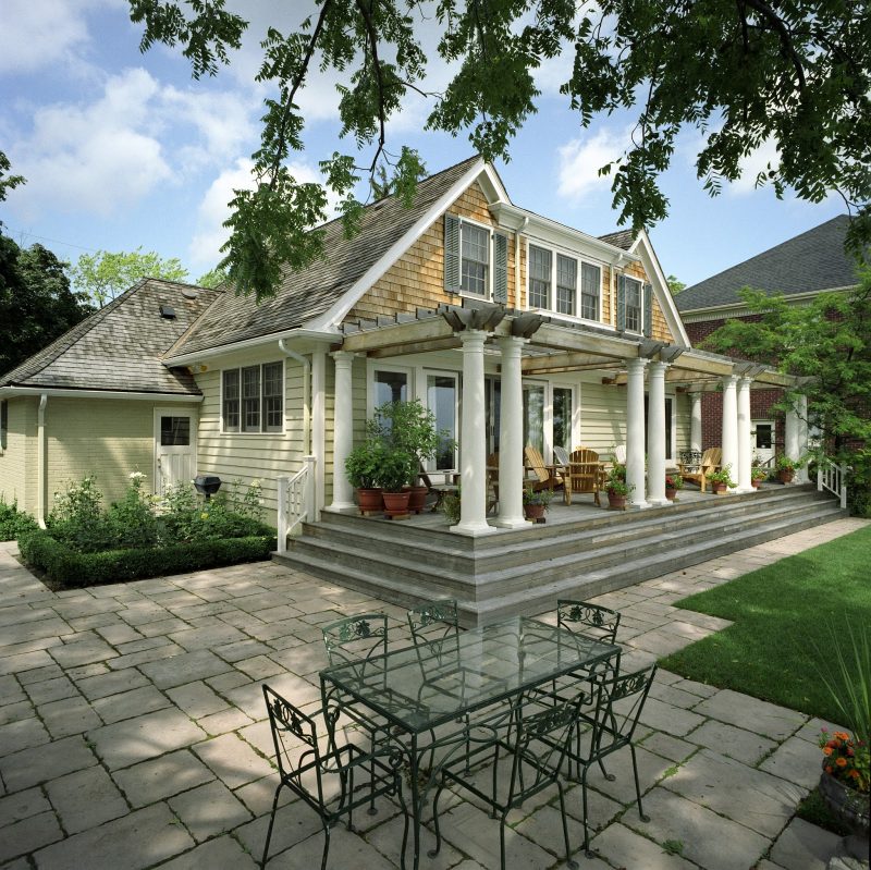 two levels for relaxing and dining with long pergola with pillars and terra cotta planters and rose garden with boxwood hedge