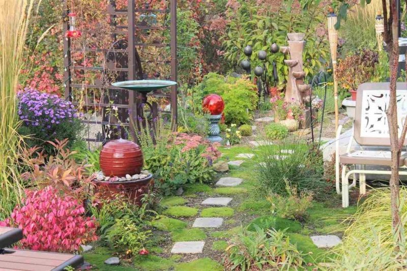 weathered copper basin with wrought iron circle base bird bath and two ball and urn fountains with 6-tier pouring pots fountain and tiki torches and square stepping stones with weathered aluminum arbor