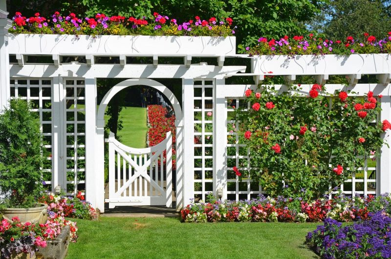 white garden gate and fence in colorful botanical garden