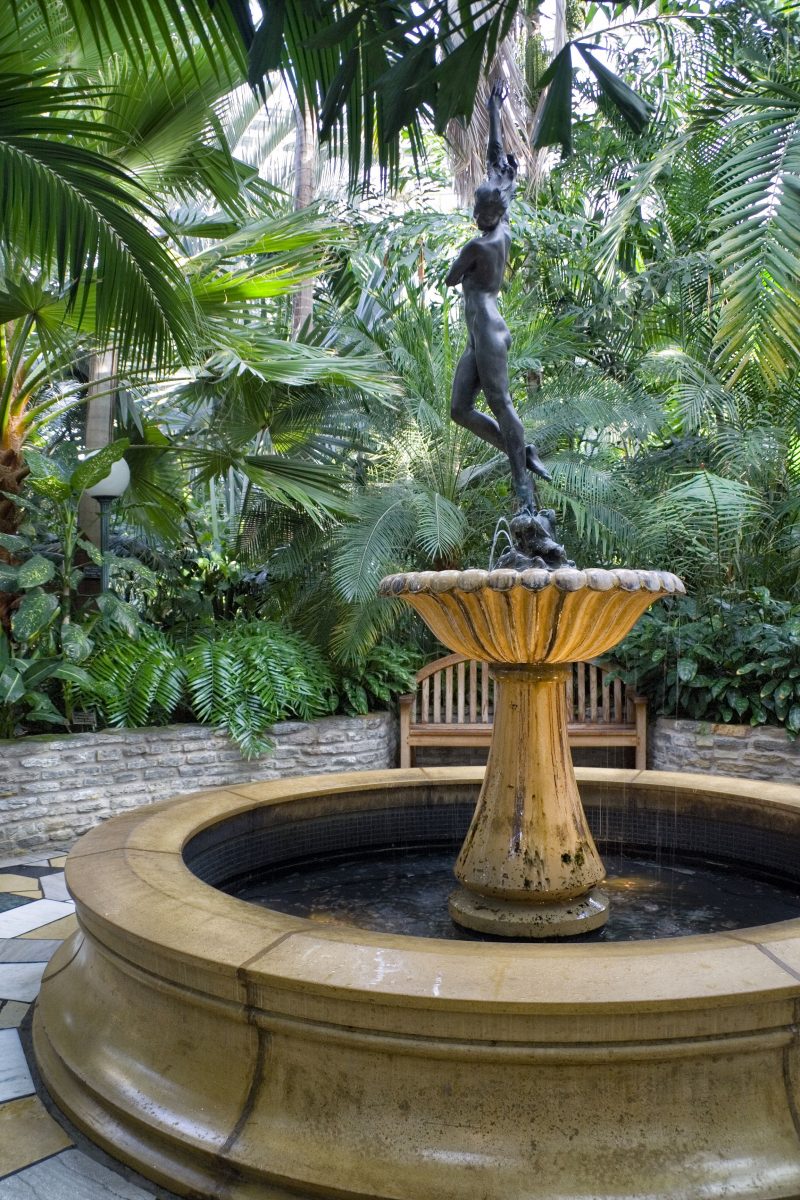 antique marble pedestal fountain with clamshell basin and marble pond base with mortared stone raised beds and custom wood bench and irregular cut tiles of contrasting colors