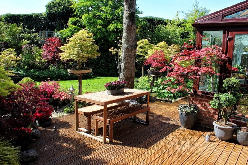 bonsai display stands with Japanese maple bonsai and white pagoda lantern and wood deck with PVC pipe edging for eco friendly watering and slid-in bench and table set