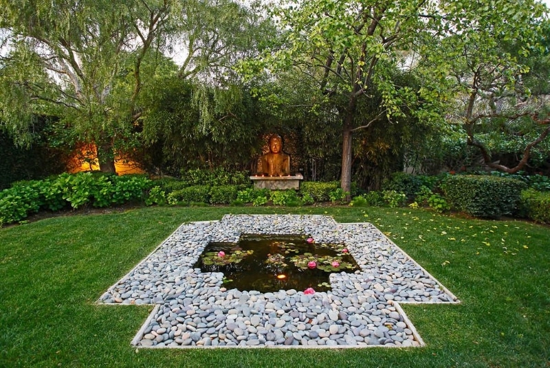 cross-shaped-natural-pond-with-pebble-parterre-following-shape-of-pond-and-wood-garden-edging-and-buddha-bust-with-under-pond-lighting