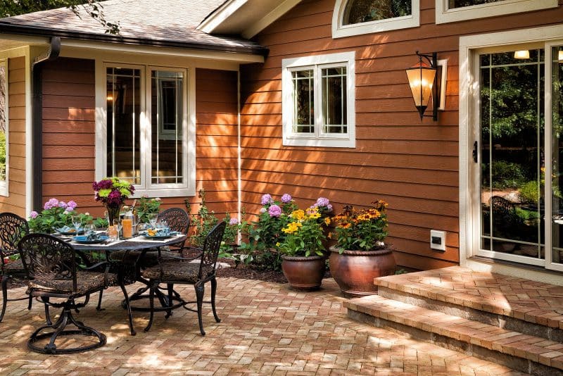 matching planters of different sizes and ceramic color contrasting with warm toned muted brick hues and herringbone pattern used for patio floors and stairs with hydrangeas parterre
