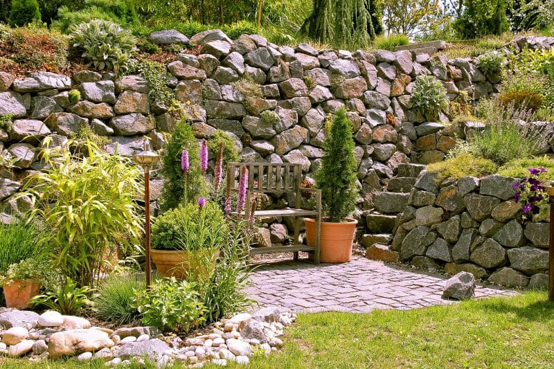 mid-size terracotta pots calling back to white-washed patio tiles with dry boulder retaining walls and natural stone slabs stairs and weathered wooden bench with Gayfeather and variety of perennials