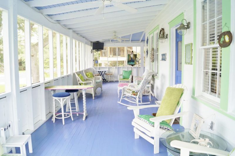 screened in porch and baby blue front door with glass panel and matching blue wooden board flooring with mint green window and door frames and antique painted pink and yellow table with twisted leg design