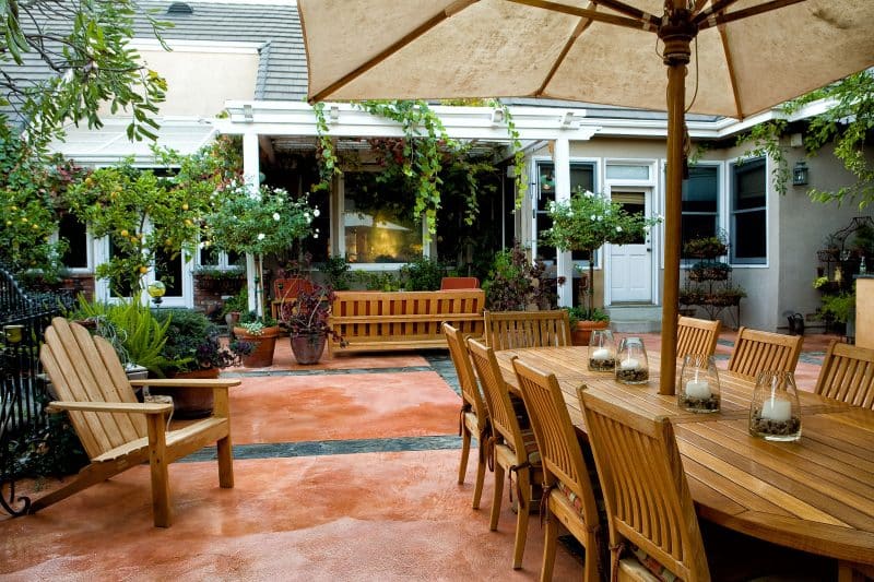 twin white rose trees in terracotta planters with iron planter stands and terracotta stained cement floor with stone inlay and potted lemons trees and DIY candle holders with three-level planter stand