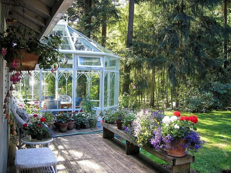 Victorian-inspired decagon sunroom and DYI wood bench doubling as planter stand with red and white geranium in terracotta planters and DIY wood hanging flower basket with copper rain chain