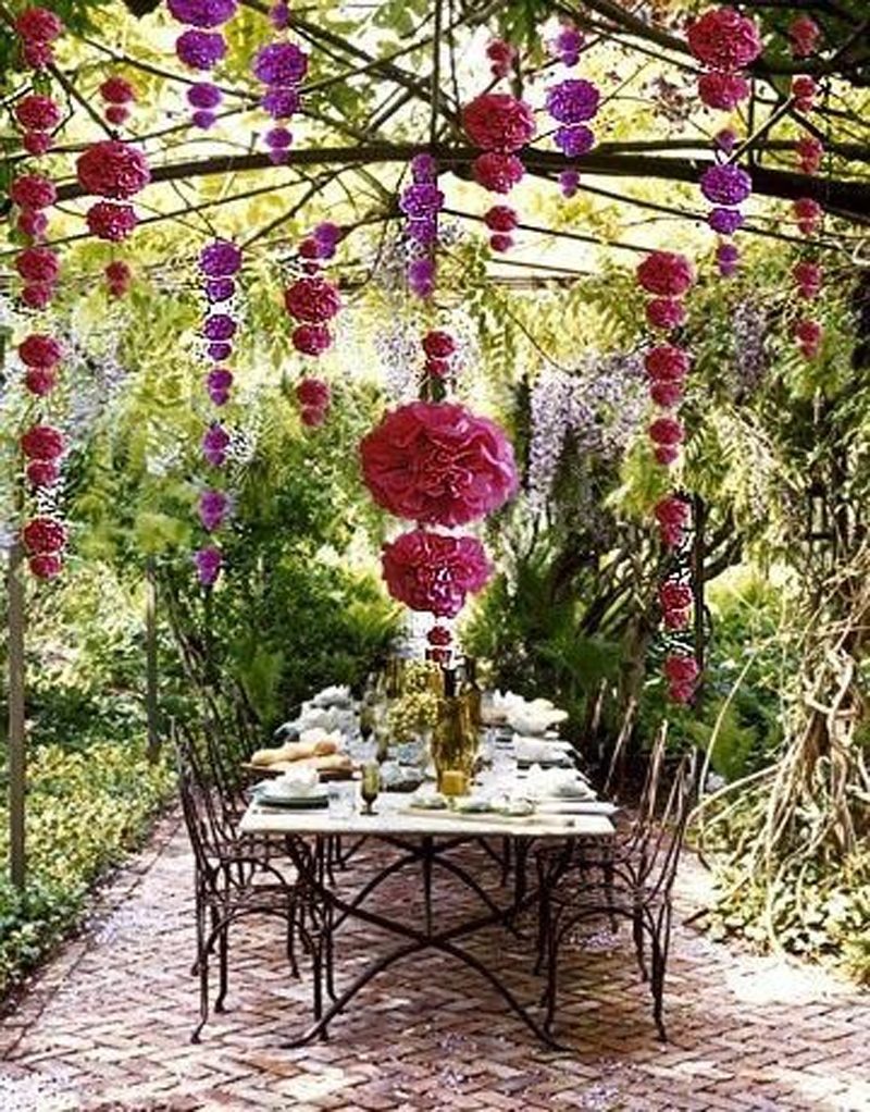 herringbone brick floor with antique bronze wrought iron dining chairs and marble topped dining table with DIY pink and purple hanging tissue paper pom pom flowers