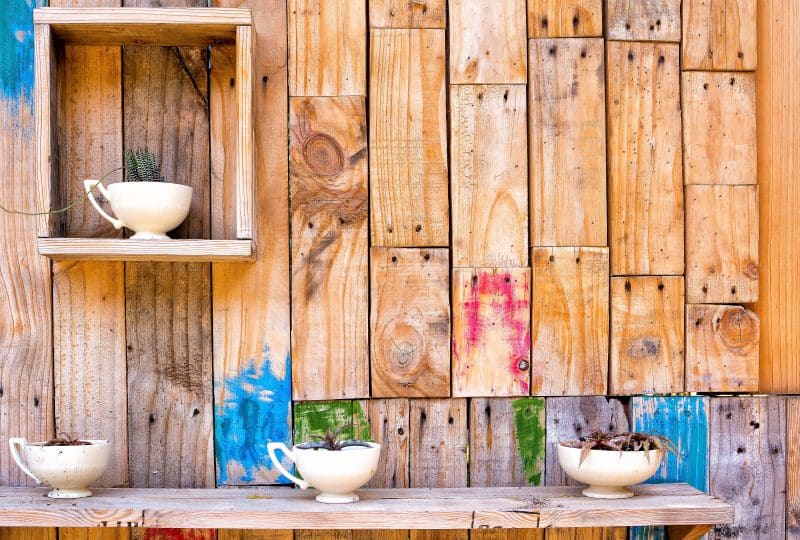 white teacup and bowl planters with DIY built-in square wooden box used as planter holder and DIY built-in wooden shelf and DIY salvaged wood board fence with paint splatters