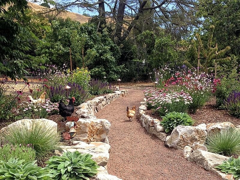 limestone boulder edging and decorative weathered copper rooster on flat boulder with antique brass garden stake lights along pathway and decomposed granite pathway